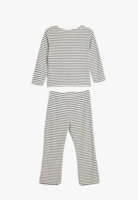 Stripet to-delt outfit bestående af en langærmet top og matchende bukser, begge i blødt, letvægtsstof med sort-hvide striber.