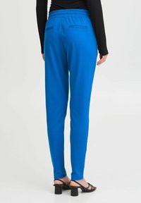 Modré, elastické kalhoty s elastickým pasem a dvěma zadními kapsami. Design je ušitý s rovnými nohavicemi a hladkou texturou.