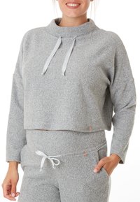 Pull gris court en tissu doux et texturé avec un col haut et des cordons fins gris ; associé à un pantalon assorti avec une taille à nouer.