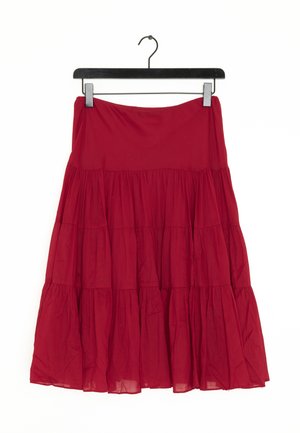 Falda midi roja de volantes con tela fruncida, colgada en una percha negra sobre un fondo blanco.