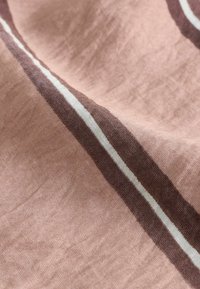 Pehme roosa kangas, millel on horisontaalne tumepruun ja valge triip, näidates tekstuuri ja õrnaid voldikesi.