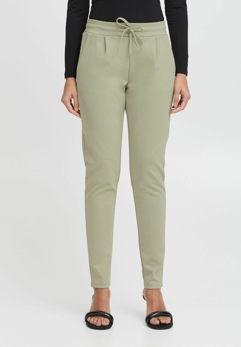 Heledad heledad rohelised püksid, millel on nööridega vöökoht, kahel esitaskul on voldid ning need on slim fit stiilis, valmistatud pehmest ja venivast materjalist.