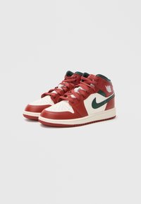 Sneakers typu mid-top z czerwonym skórzanym wierzchem, białymi skórzanymi akcentami i zieloną haftowaną logo Nike po boku. Posiada perforowany nos.
