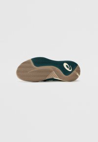 Sport-Schuhsohle aus strukturiertem braunem Gummi mit einem Zickzackmuster, hellgrünen Akzenten und einem auffälligen Logo.