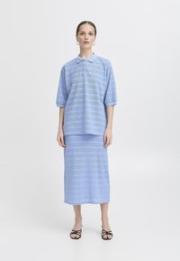 Completo in maglia azzurro chiaro composto da una polo a maniche corte con colletto e una gonna lunga abbinata, caratterizzato da strisce orizzontali testurizzate.