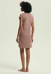 Sukienka z krótkim rękawem, długości do kolan w kolorze przykurzonego różu, wykonana z bawełny. Prosty fason z okrągłym dekoltem i luźnym krojem, charakteryzująca się miękką teksturą i brakiem wzorów.