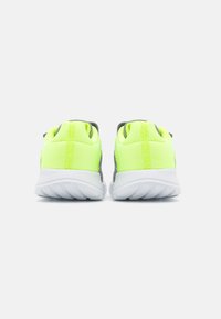Zapatillas deportivas en amarillo brillante y gris con parte superior de malla, suela blanca acolchada y talón texturizado para mayor agarre. Diseñadas para ofrecer comodidad y soporte.