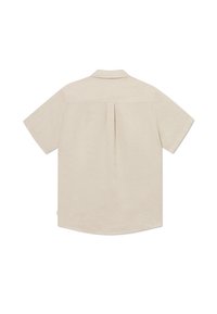 Chemise beige à manches courtes avec un empiècement dos et un pli central, étendue à plat montrant le dos.