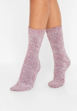 Chaussettes tricotées dans un motif chiné rouge et blanc, de longueur mi-mollet, avec une texture douce et une bordure côtelée pour un maintien sécurisé.