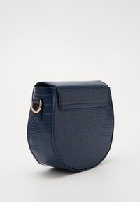 Borsa blu navale, testurizzata con motivo coccodrillo, forma curvata, chiusura a pattina magnetica e accessori in ottone dorato sui lati.