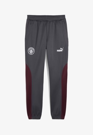 Pantalones deportivos grises con un panel lateral burdeos, cinturilla elástica, logo de Manchester City y logo de Puma en la parte delantera. Textura suave.