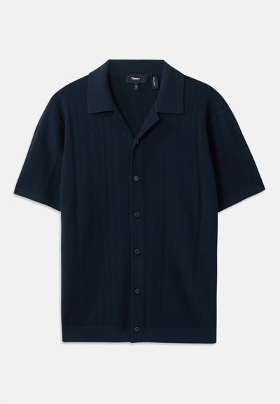 Kortermet marineblå polo skjorte med teksturert mønster, knappestolpe foran og flat krage. Laget av et lett stoff.