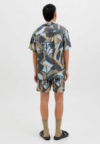Kortærmet skjorte og shorts sæt i blå, brun og beige bladmønster; letvægtsstof, afslappet pasform, suppleret med mørke sandaler og beige sokker.