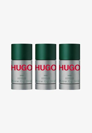 Tre deodorantstænger med grønne låg og sølvbeholdere. Etiketten står der "HUGO MAN," med produktdetaljer i hvid og grøn tekst.