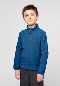 Giacca in pile blu con colletto alto e zip completa. Presenta un logo sul lato sinistro del petto e polsini elasticizzati per una vestibilità aderente.