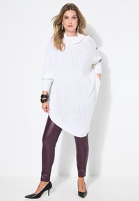 Witte gebreide tuniek met een col kraag, voorzien van kabelbrei details, zijzakken en knoopaccenten, gecombineerd met bordeaux leren leggings.