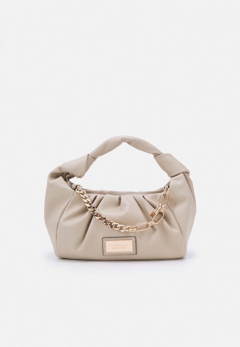 Sac à main beige doux avec poignée torsadée, détail en chaîne dorée et une étiquette métallique rectangulaire au centre avant.
