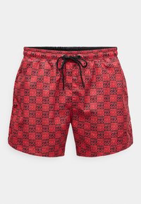 Red swim shorts featuring a graphic pattern with the text "HUGO" in black, elastic waistband with drawstring, and side pockets.