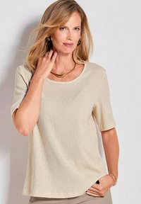 Beige top met korte mouwen, voorzien van een subtiele verticale textuur en een ronde hals. Beschikt over een lichte A-lijn vorm en zachte, ademende stof.