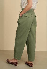 Olijfgroene wijde broek met hoge taille, zijzakken en twee achterzakken, gecombineerd met ballet flats met panterprint.