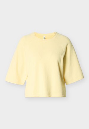 Pulover galben scurt cu mâneci raglan scurte, realizat dintr-un material moale, având guler și tiv côtelat. Design simplu, fără modele sau accente.