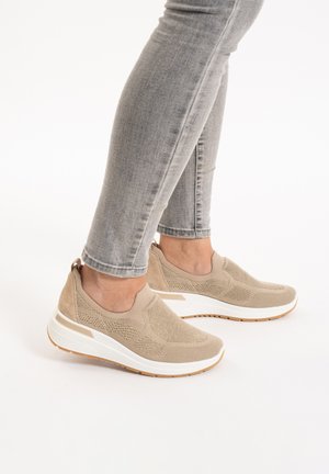 Sneakers slip-on beige realizzati in maglina testurizzata e suede, con suola in gomma bianca e linguetta sul retro, indossati con jeans skinny grigi.
