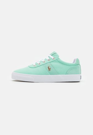 Niski miętowy zielony sneaker z białymi sznurówkami, białą gumową podeszwą i małym wyszywanym logo gracza polo z boku.