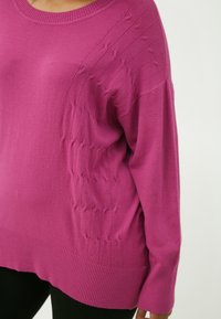 Rosa gestrickter Pullover mit geripptem Saum und strukturierten Details an der Schulter, mit einem lässigen Schnitt und weichem Stoff.