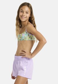Haut de bikini multicolore avec un motif géométrique en vert et violet, associé à un short de bain violet clair arborant un logo blanc.