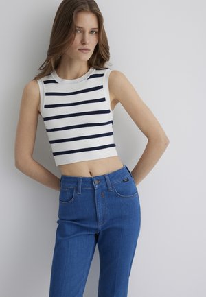 Weißes, kurzes Tanktop mit marineblauen Streifen, kombiniert mit hochgeschnittenen blauen Jeans. Rippstruktur, runder Ausschnitt und Fünf-Taschen-Design.