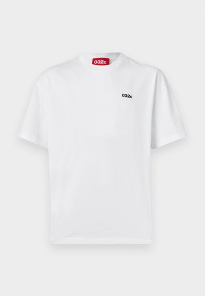 Hvid bomulds T-shirt med korte ærmer. Har et lille sort logo "032c" på venstre bryst og et rødt mærke ved halsen.