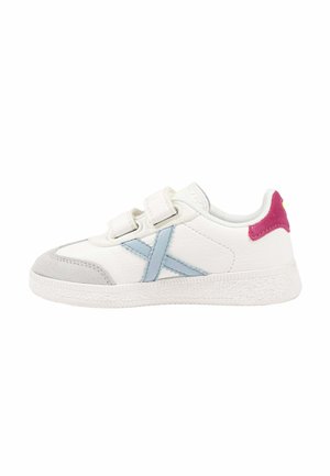 Zapatilla blanca con rayas laterales azul claro, puntera gris, lengüeta rosa en el talón y dos tiras de velcro blancas.