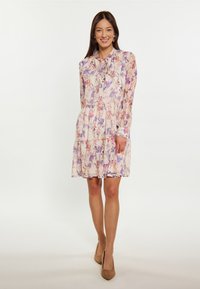 Blumenkleid in hellem Pfirsich, mit langen Ärmeln, Krawattenhalsausschnitt, gestuftem Rock und einer Mischung aus lila und rosa Blumen.
