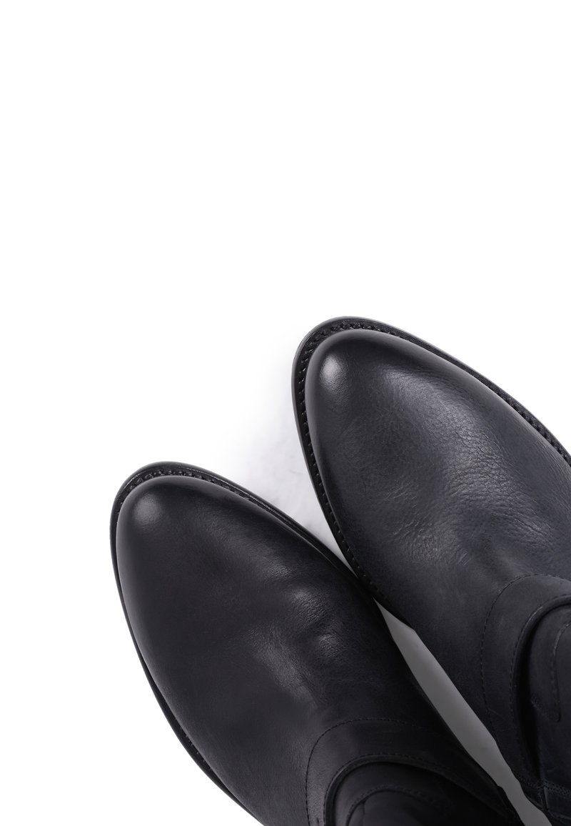 Czarne skórzane botki za kostkę o gładkiej fakturze, zaokrąglonych noskach i minimalnych detalach przeszycia na krawędziach. Płaskie solówki zwiększają komfort.