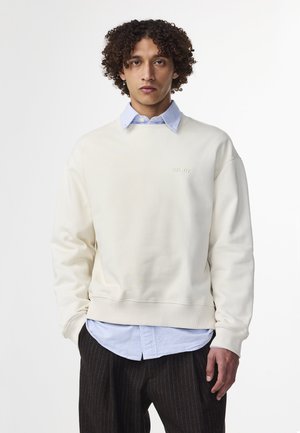 Cremfarbener Sweatshirt aus weichem Stoff, mit rundem Ausschnitt, gerippten Bündchen und einem dezenten gestickten Logo auf der Brust.