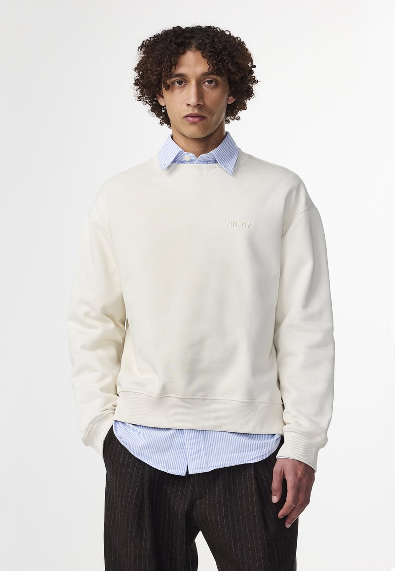 Cremfarbener Sweatshirt aus weichem Stoff, mit rundem Ausschnitt, gerippten Bündchen und einem dezenten gestickten Logo auf der Brust.