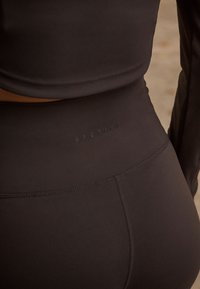 Leggings atletici neri realizzati in materiale elastico, con una fascia alta in vita su cui è incisa la parola "ACTIVE". Texture liscia.