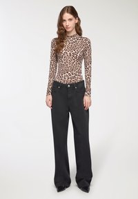 Body a maniche lunghe con stampa leopardata, abbinato a pantaloni larghi in vita alta neri con tasche frontali e dettagli in metallo argentato.