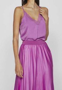 Purple sleeveless top with lace trim and a silky pleated skirt, both in a vibrant shade, highlighting smooth texture and soft draping.