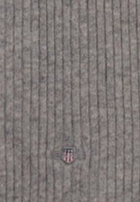 Tessuto ribbed grigio con un emblema sottile al centro che presenta accenti rossi, bianchi e blu, caratterizzato da una consistenza morbida e linee verticali.