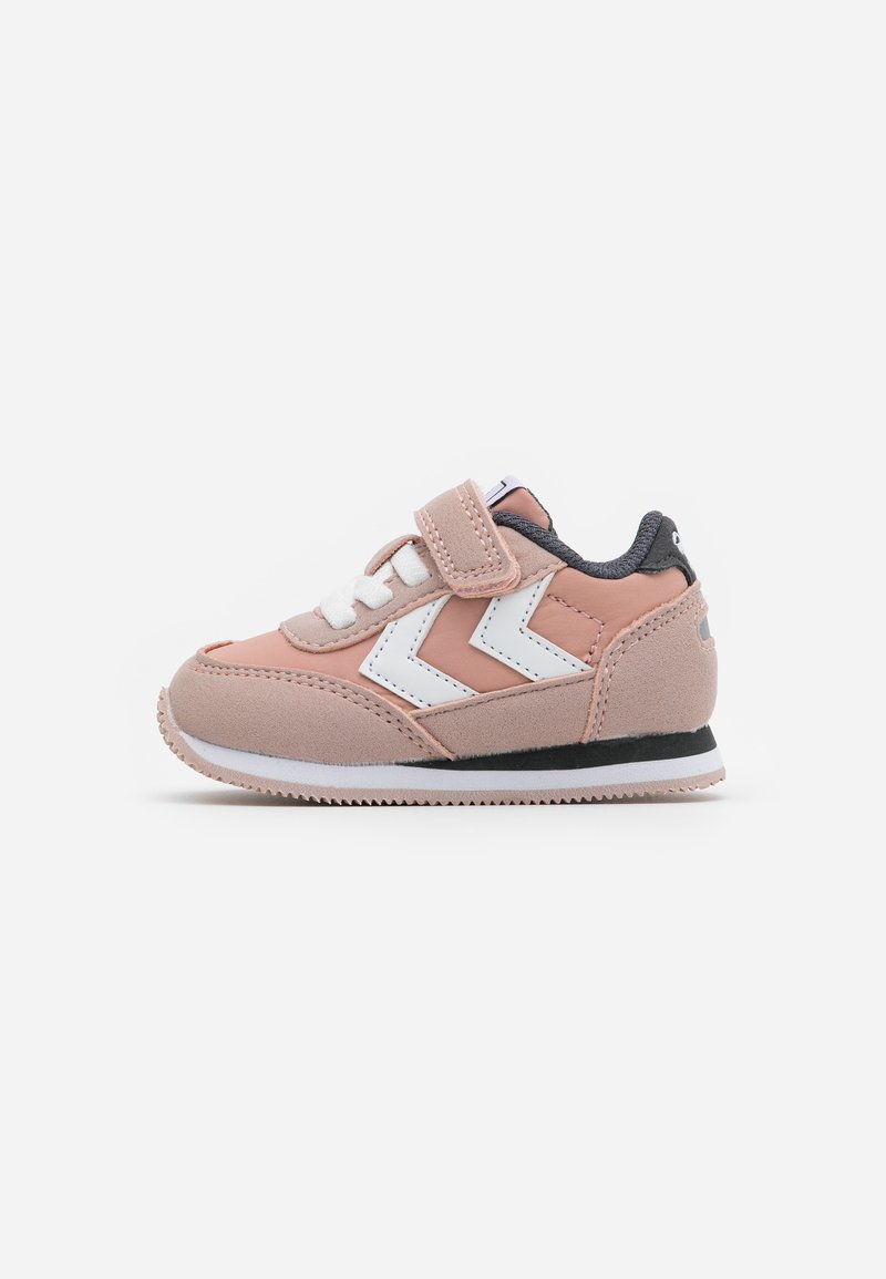 Rosa Wildleder-Sneaker mit einem weißen Zickzackdesign, Schnürverschluss und Klettverschluss, schwarzer Gummisohle und grauen Akzenten.