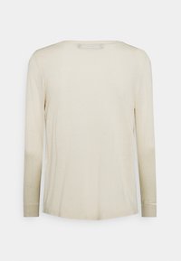 Světle béžové tričko s dlouhým rukávem, kulatým výstřihem a měkkou texturou. Má volný střih a minimální stehy na švech.
