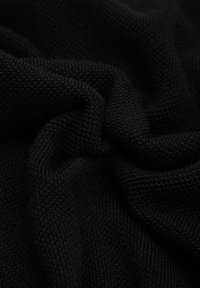 Czarna dziana tkanina o teksturowanym, miękkim wyglądzie, z ciasno ułożonymi ściegami i subtelnym naciągiem. Materiał wygląda gładko, ale jednocześnie jest przytulny.