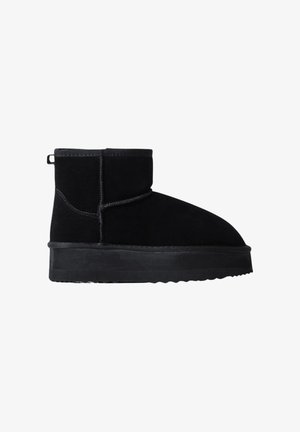 Stivale alla caviglia nero in suede con suola piatta in gomma testurizzata e design a cuciture lungo il corpo; presenta un cricco posteriore per indossarlo facilmente.