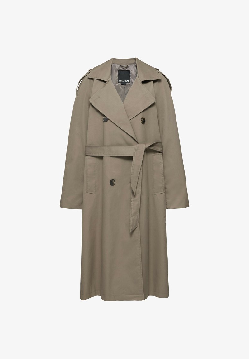 Trench-coat beige croisé avec larges revers, détails de boutons, brides aux épaules, poches latérales et ceinture à la taille.