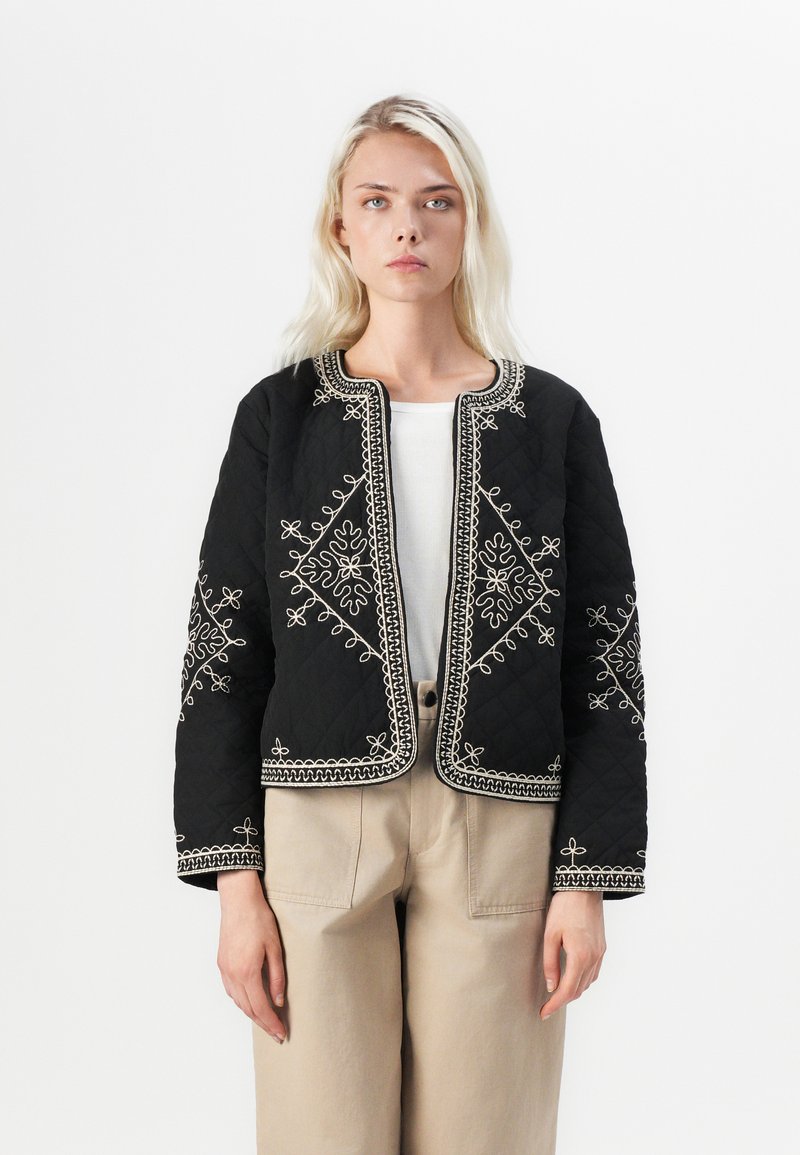 Black quilted jacket featuring white embroidery along the edges and floral patterns. The design has a round neckline and cropped sleeves.