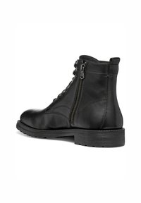 Botín de cuero negro hasta el tobillo con punta redondeada, cremallera lateral y diseño de cordones. Presenta un acabado texturizado y una suela de goma negra resistente.