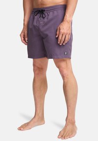 Μωβ μαγιό με ελαστική ζώνη, κορδόνι και μικρή μαύρη ετικέτα στο αριστερό μέρος. Ελαφρύ ύφασμα, κοπή μέχρι το γόνατο.