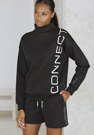 Black pullover sweatshirt with tall collar and white lettering "CONNECT" on the side, paired with black shorts featuring branding. Smooth texture.