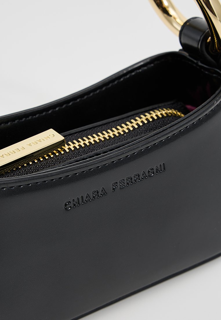 Schwarze Lederhandtasche mit einem goldenen Reißverschluss, geprägtem Logo und einer glatten Textur. Das Innere weist eine kontrastierende Stoffauskleidung auf.